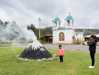 Personas se fotografían con una réplica del Cotopaxi en Ticatilín, una comunidad aledaña al volcán.