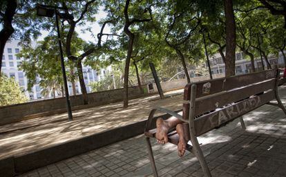 Un hombre reposa en un banco de la plaza de Josep Maria Folch i Torres.