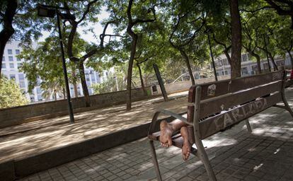 Un hombre reposa en un banco de la plaza de Josep Maria Folch i Torres. 