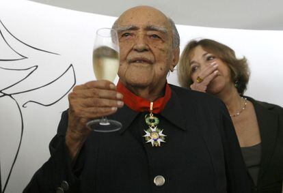 Vera Niemeyer se emociona  detr&aacute;s de su esposo, el arquitecto brasile&ntilde;o Oscar Niemeyer, mientras comparte  un brindis. Niemeyer recibi&oacute; una  medalla de honor del embajador de Francia en Brasil, Antoine Pouilliete, para celebrar su cumplea&ntilde;os n&uacute;mero 100, en R&iacute;o de Janeiro.