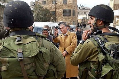 El candidato palestino Basam Salhi, en el centro, pasea ayer en Hebrón, ante la mirada de los soldados israelíes.