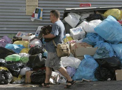 Un vecino de San Fernando pasa junto a la basura acumulada junto a un contenedor.