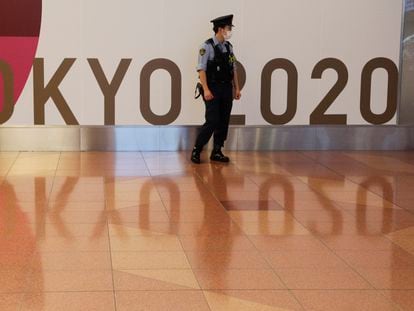Un policía japonés monta guardia ante un cartel de Tokio 2020 en el aeropuerto tokiota de Haneda