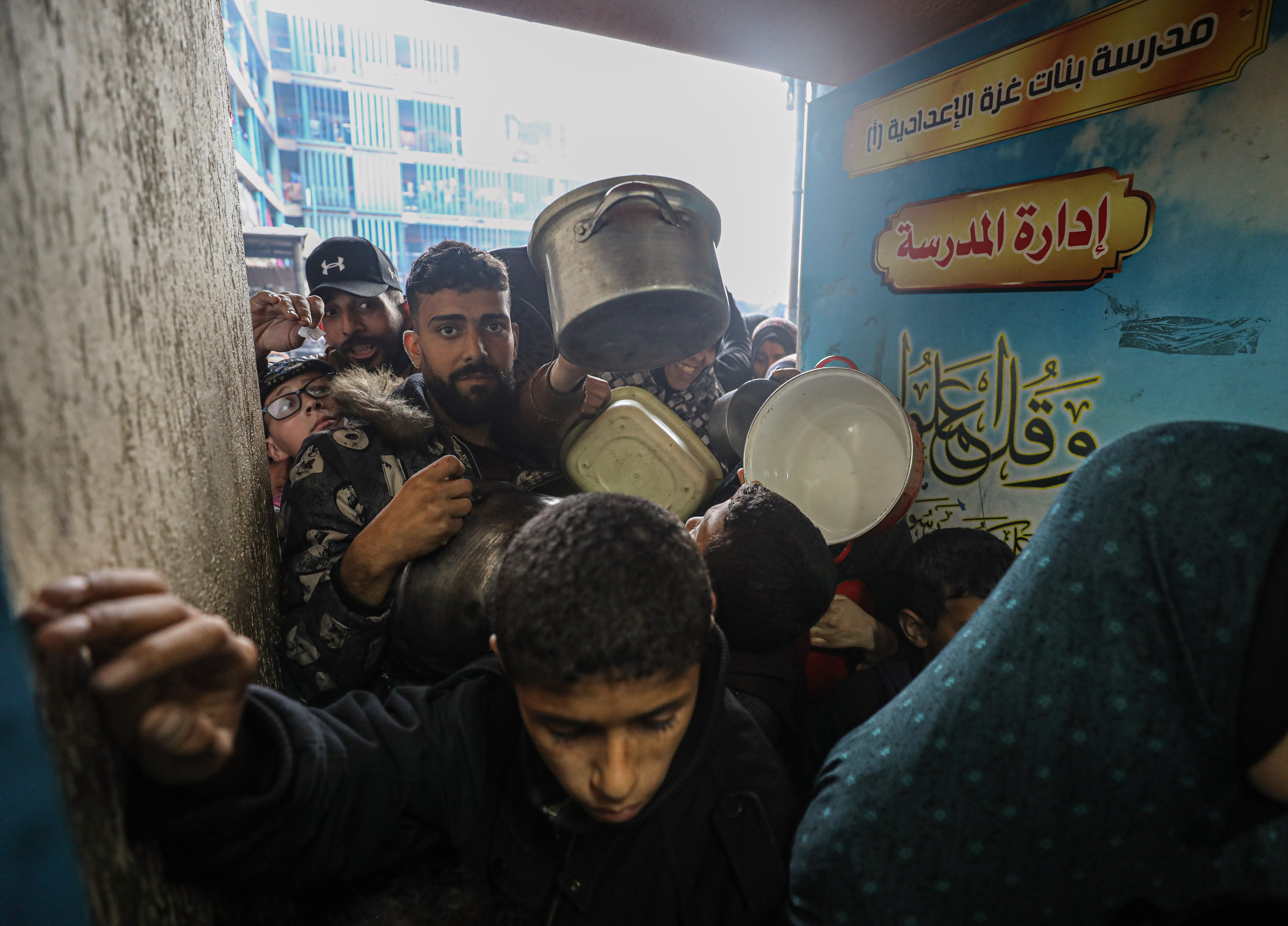 Un grupo de palestinos espera con ollas vacías a recibir comida de las ONGs en la ciudad de Gaza este lunes.