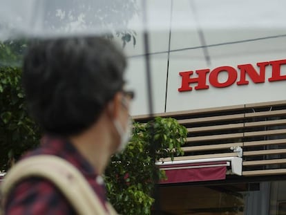 Un hombre con mascarilla mira el logo de Honda.