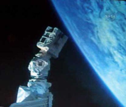 Con la tierra al fondo, el brazo robot del Brazo Sensor de Sistemas Orbital (OBSS) se usa para revisar el transbordador espacial <i>Discovery</i>.