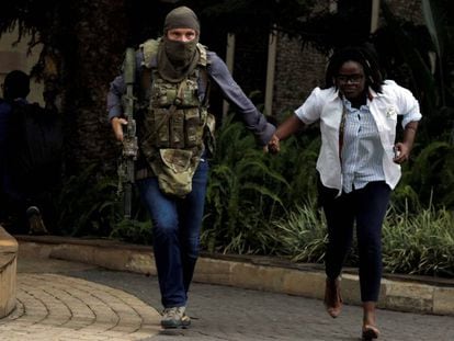 Un miembro de las fuerzas de seguridad kenianas evacúa a una mujer del hotel Dusit que fue atacado en Nairobi a mediados de enero.