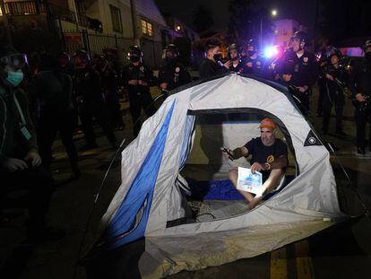 Un manifestante instala una carpa frente a la policía en la sección Echo Park de Los Ángeles, el día de ayer.