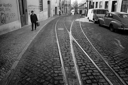 A passerby walks down a street in the popular Chiado neighborhood, on the characteristic cobblestones (calçada) of Lisbon.