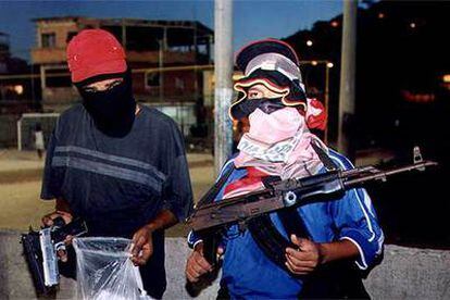 Dos niños enmascarados sostienen drogas y armas (pistolas y un fusil) en Río de Janeiro (Brasil).