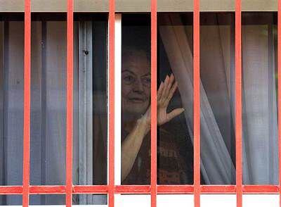 Una mujer se asoma a la ventana de la planta baja de la residencia  Juan XXIII, en Alcobendas.