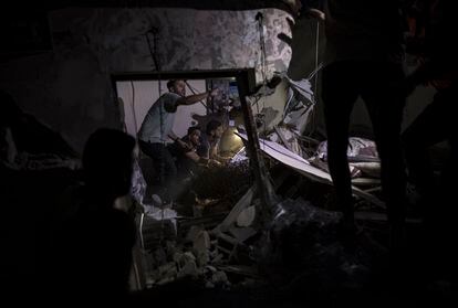 Palestinos buscan víctimas y supervivientes entre los escombros de un edificio residencial destruido tras un ataque israelí, este lunes en Jan Yunis. 