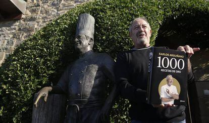 Karlos Arguiñano posa con su último libro junto a una estatua erigida en su nombre en Zarautz (Gipuzkoa).