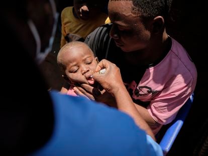 Un padre sostiene a su hijo mientras un trabajador le administra la vacuna contra la poliomielitis en el campo de refugiados de Dzaleka, en Malaui.