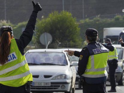 Varios agentes de Policía Nacional dan el alto a un vehículo en un control de movilidad en la parroquia de O Castiñeiriño (Santiago de Compostela), en la entrada y salida Santiago hacia Ourense (Galicia).