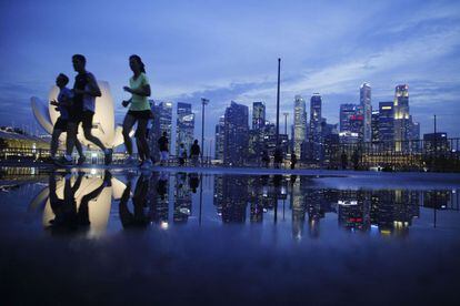 Jóvenes corredores pasan junto al skyline de la zona financiera de Singapur.