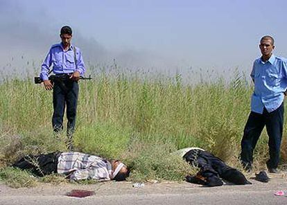 Policías iraquíes permanecen junto a dos cadáveres, atados y con los ojos vendados, encontrados ayer a las afueras de Bagdad.