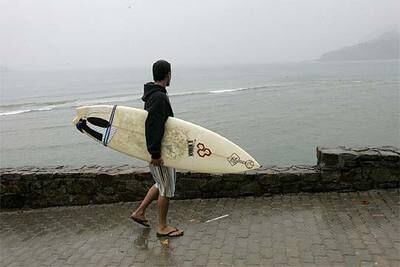 Un surfista pasea con su tabla por Mundaka, meca mundial para los aficionados a este deporte.