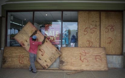 Un treballador retira les taules de fusta dels seus aparadors després del pas de l'huracà Matthew a Kingston (Jamaica).