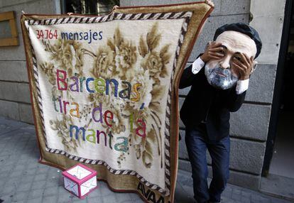 Un hombre protesta en el exterior de la Audiencia Nacional, con una careta del presidente del Gobierno Mariano Rajoy, durante la declaración de Luis Bárcenas ante el juez Pablo Ruz.