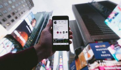 Un hombre sostiene en el aire su móvil con la app de Instagram abierta.