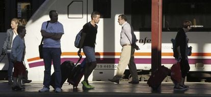 Varios pasajeros de tren con equipajes caminan por un and&eacute;n de la estaci&oacute;n de Chamart&iacute;n. 