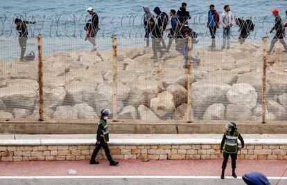 Agentes de seguridad marroquíes montan guardia mientras un grupo de migrantes caminan por la costa en la ciudad norteña de Fnideq, en un intento de cruzar la frontera, este martes.