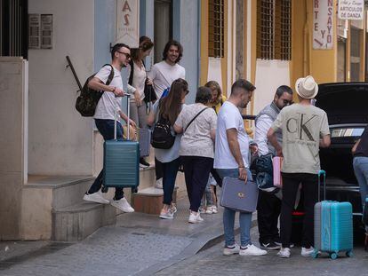 Varios jóvenes cargados con maletas salen de un piso turístico en Sevilla.