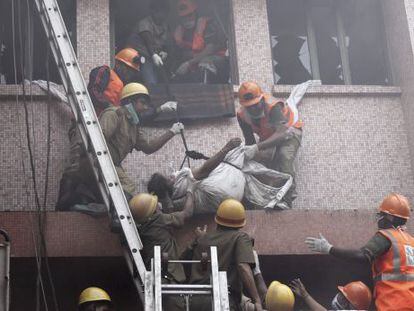 Trabajadores de los equipos de rescate evacúan el cuerpo sin vida de una paciente de un hospital de AMRI en Calcuta (India) tras un incendio
