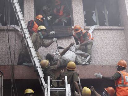 Trabajadores de los equipos de rescate evac&uacute;an el cuerpo sin vida de una paciente de un hospital de AMRI en Calcuta (India) tras un incendio