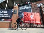 A man cycles past banners outside of Anfield Stadium, Liverpool, England protesting against the clubs decision to join the European Super Leaguer, Tuesday April 20, 2021. Chelsea and Manchester City are preparing to dramatically abandon plans to join a breakaway Super League threatening to implode the project by a group of elite English, Spanish and Italian clubs less than two days after it was announced.  (Peter Byrne/PA via AP)