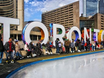 Varios jóvenes esperan en una pista de hielo instalada en el centro de Toronto.