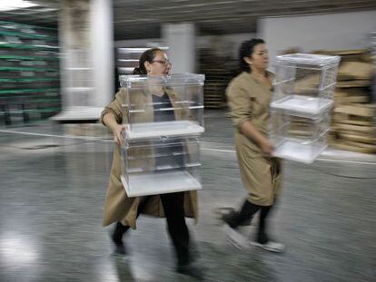 Dos mujeres trasladan urnas en un local electoral de Sevilla.
