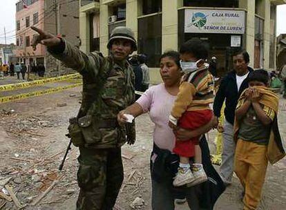Un militar peruano da indicaciones a una mujer en una de las calles de Pisco.