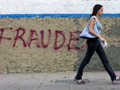 Una mujer camina frente a una pintada en Caracas.