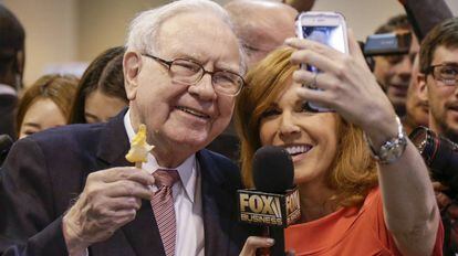Warren Buffett posa para una foto con una periodista en la junta de Berkshire Hathaway.