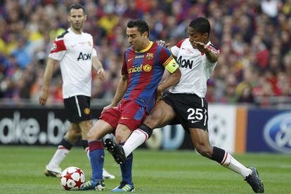 Xavi controla el balón ante Valencia y la mirada de Giggs.