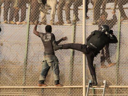 Un grupo de inmigrantes subsaharianos se enfrenta a un polic&iacute;a tras saltar la valla de Melilla.