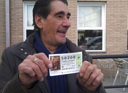 Un hombre, en un bar de Huesca, muestra un décimo agraciado con el número 58.268, el premio gordo.