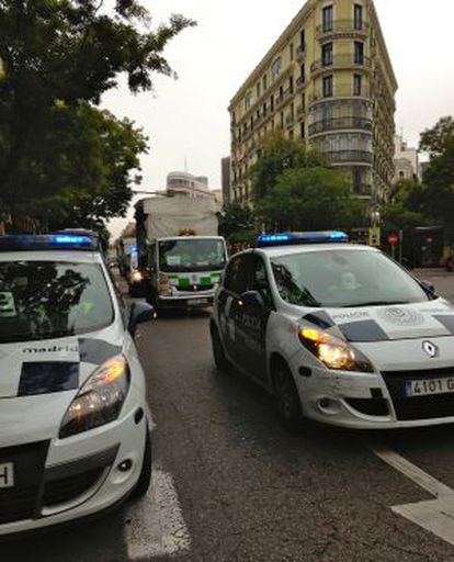 Vehículos de la policía municipal escoltan furgonetas de servicios mínimos de limpieza por el centro de Madrid.