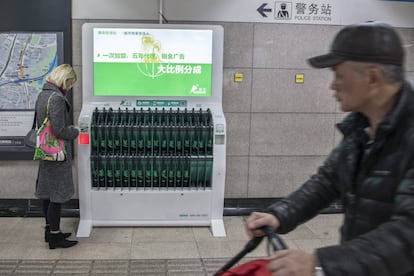 Una chica saca un paraguas, que se paga por horas, de un dispensador situado en una parada de metro de Shanghái.