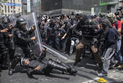 Un policía atidisturbios cae al suelo en el enfrentamiento con los jóvenes "anarquistas", según se identificaron ellos mismos ante los medios de comunicación.