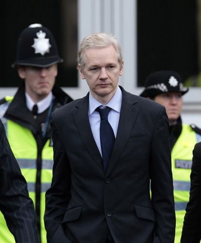 Julian Assange, escoltado por policías, momentos antes de comparecer ante la prensa