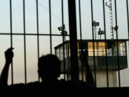 Un recluso mira desde detrás de las rejas una torre de seguridad en la prisión estatal de Nayarit, en Tepic (México).