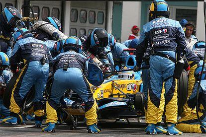 Los mecánicos de Renault, durante la operación de cambio de neumáticos del coche de Fernando Alonso.