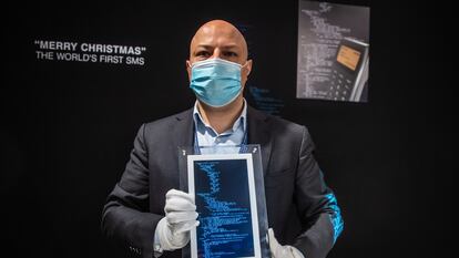 Un operario muestra el marco con el código del primer SMS de la historia.