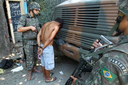 Dos soldados arrestan arrestan a un presunto narcotraficante en una favela de Río de Janeiro.