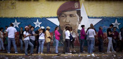 Cola en Caracas ante un mural de Hugo Ch&aacute;vez.