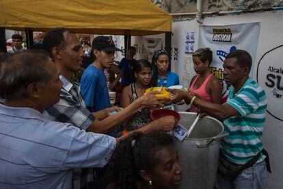 Ciudadanos venezolanos reciben comida, este sábado, a las afueras de Caracas.