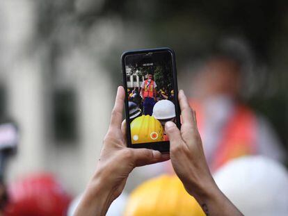 Un rescatista graba en su celular al hijo de una víctima, que agradece a los voluntarios.